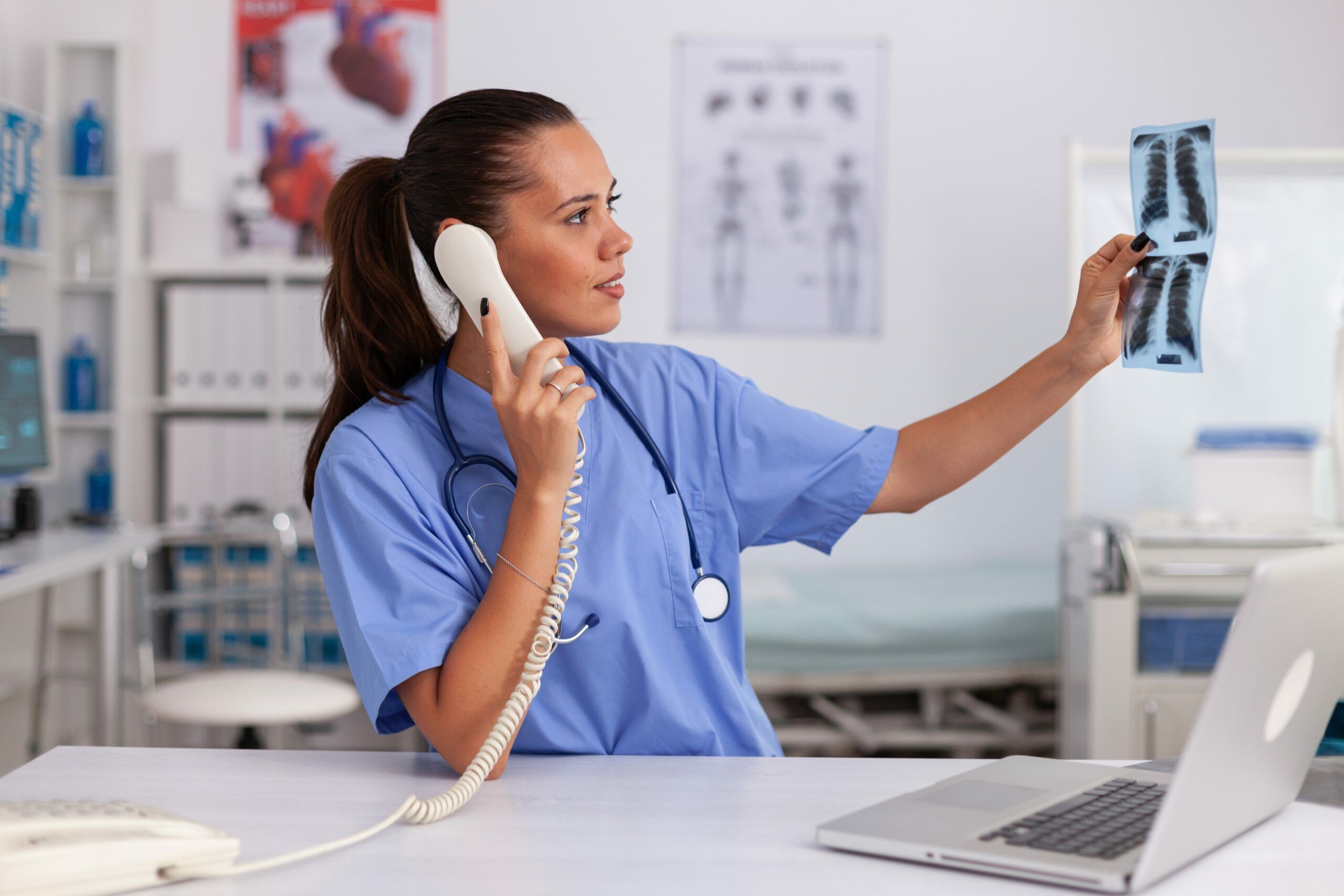 Medizinische Krankenschwester hält Patienten Radiographie im Krankenhaus Büro im Gespräch mit Arzt am Telefon. Gesundheitspflege Arzt sitzt am Schreibtisch mit Computer in modernen Klinik Blick auf Monitor.